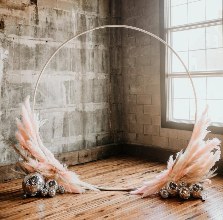 A thin hoop arbor on a base of blush pink flamingo feathers and mirrored disco balls
