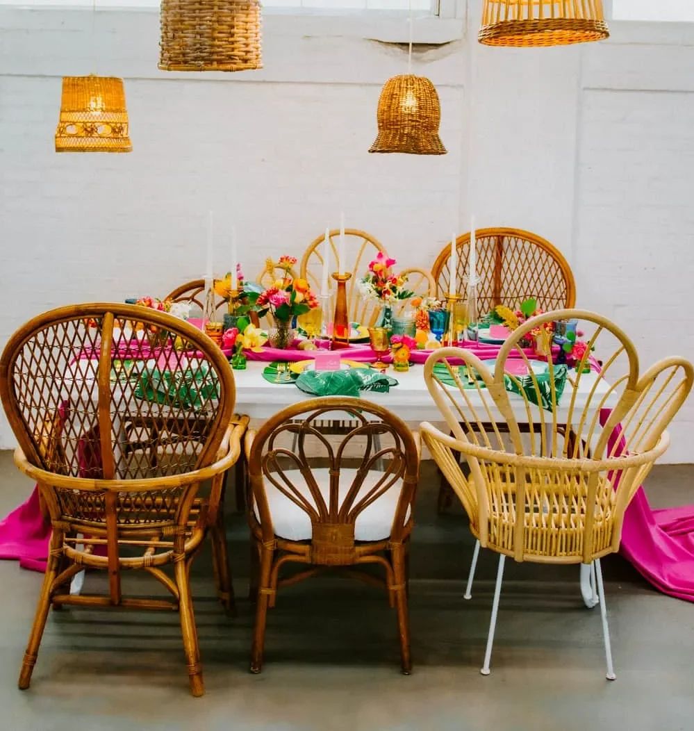 Wedding dining table decked out in bright tropical colors and brown whicker furniture