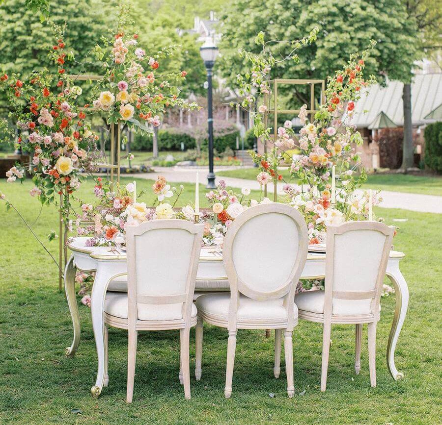 A white wooden dining table and chairs, lined with flowers in a city park